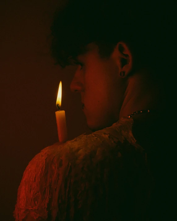 a woman holding a lit candle in front of her face, an album cover, inspired by Elsa Bleda, unsplash, androgynous person, profile image, cai xukun, lgbtq