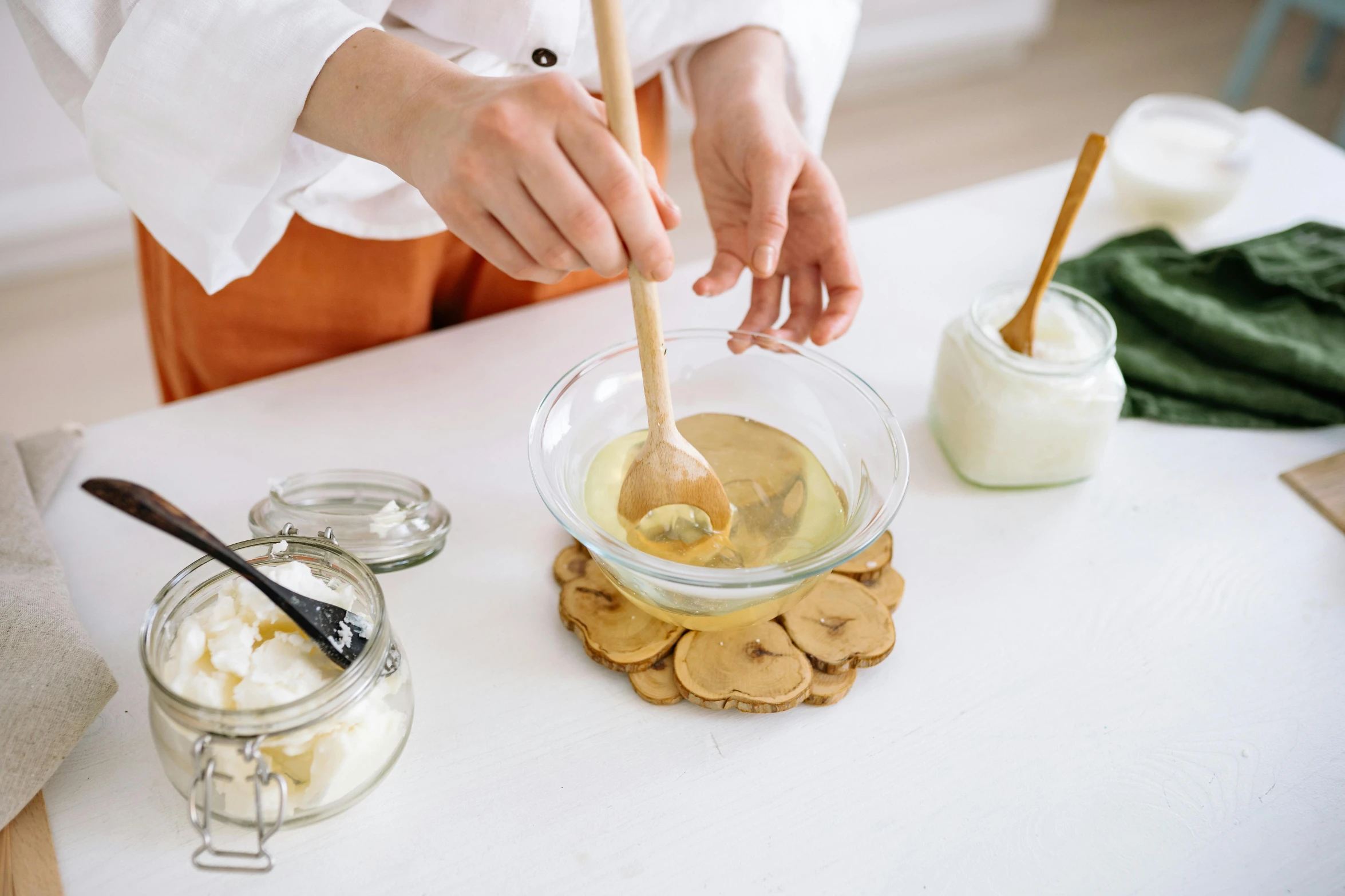 a woman mixing ingredients in a bowl on a table, a still life, trending on pexels, blonde cream, holding a wooden staff, crisp clean shapes, manuka