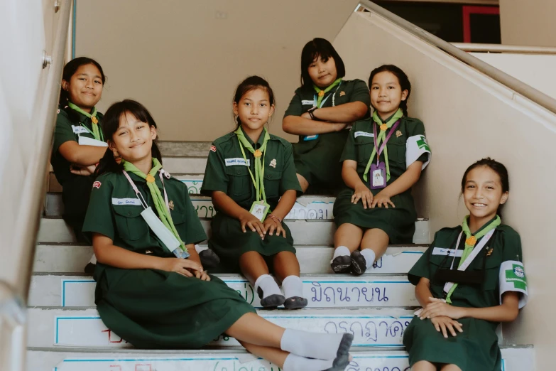 a group of young girls sitting on top of a flight of stairs, pexels contest winner, ashcan school, thailand, wearing green, scout boy, avatar image