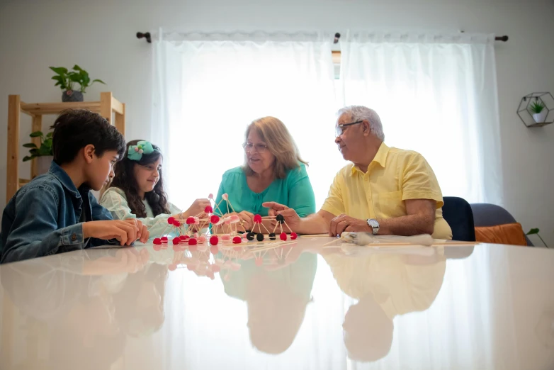 a group of people sitting around a table, playing, profile image, family, blanca alvarez