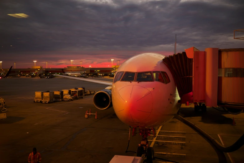 a large jetliner sitting on top of an airport tarmac, by Jeffrey Smith, pexels contest winner, red and orange glow, pink, instagram post, front lit