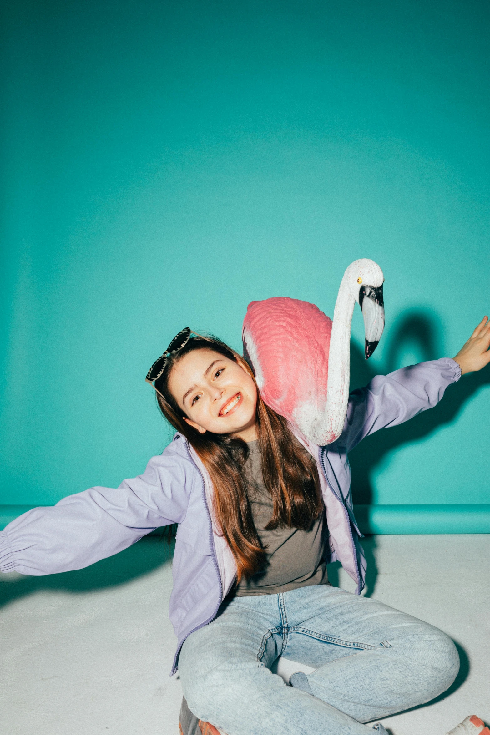 a woman sitting on the floor with a flamingo pillow, by Julia Pishtar, pexels contest winner, dilraba dilmurat, pose(arms up + happy), cyan photographic backdrop, headshot profile picture