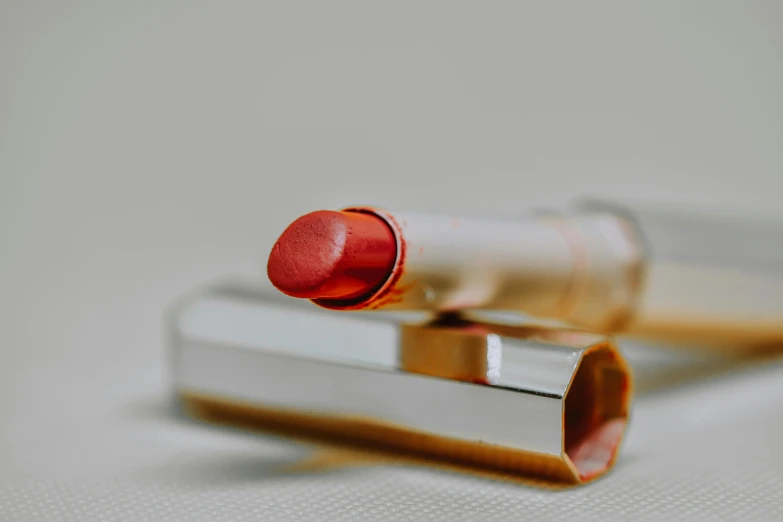a close up of a red lipstick on a white surface, pexels contest winner, hyperrealism, brown, pink, silver red, post-processed
