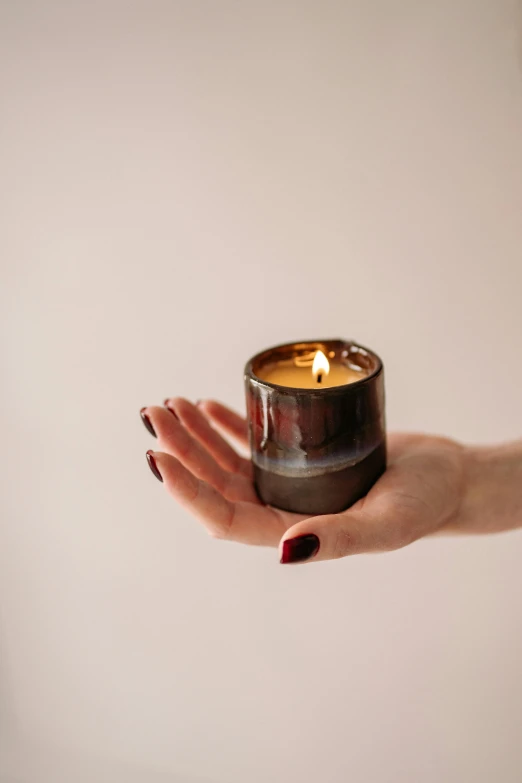 a person holding a candle in their hand, glaze, full product shot, earthy, centred