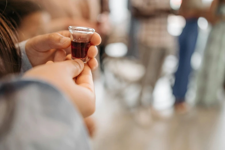 a close up of a person holding a glass of wine, baptism, drinking cough syrup, everyone having fun, standing inside of a church