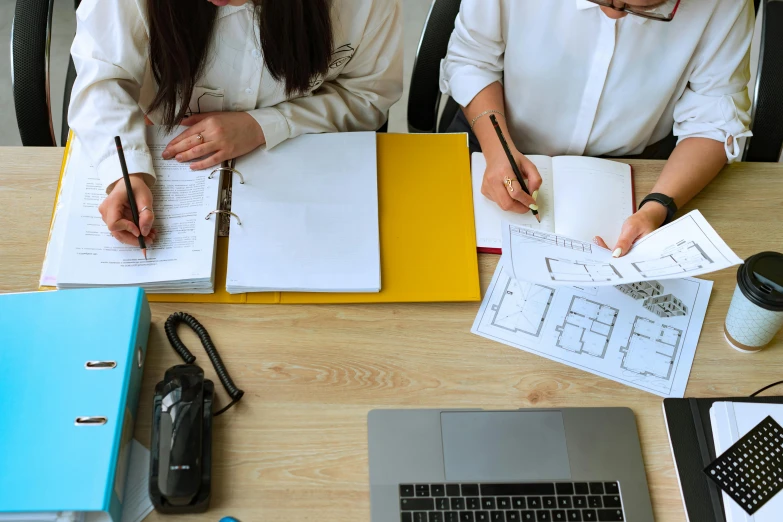 a couple of people that are sitting at a table, a cartoon, pexels contest winner, arbeitsrat für kunst, architectural plans, background image, schematic in a notebook, in office