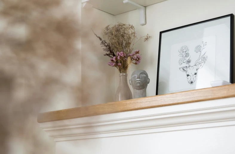 a vase filled with flowers sitting on top of a mantle, by Richmond Barthé, trending on unsplash, light and space, simple wood shelves, detailed faces looking up, white wall, detailed product shot