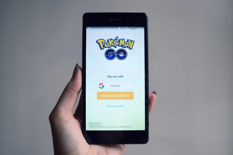 a person holding a cell phone with a pokemon app on the screen, by Carey Morris, pexels, gold, google, splash screen, leaked