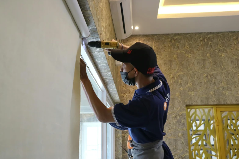 a man in a blue shirt is painting a wall, by Francis Helps, hyperrealism, hanging scroll on wall, jakarta, hd quality, plaster