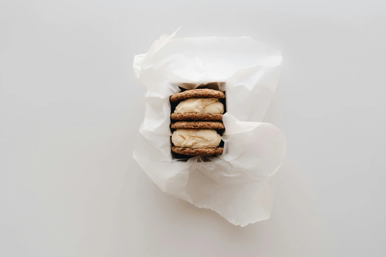 a box of cookies sitting on top of a white table, unsplash, brown and white color scheme, three fourths view, manuka, dessert