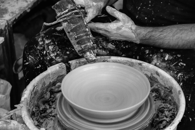 a person making a bowl on a potter's wheel, a black and white photo, by Daniel Gelon, pexels contest winner, process art, pouring, 15081959 21121991 01012000 4k, made of glazed, detail