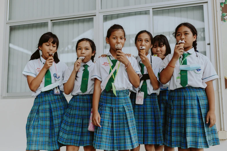 a group of young girls standing next to each other, by Emma Andijewska, pexels contest winner, sumatraism, eating ice - cream, school uniform, background image, young girl playing flute