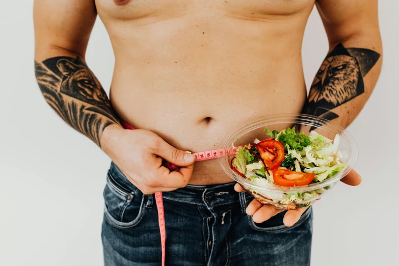 a close up of a person holding a bowl of food, trending on pexels, muscular body tattooed, salad, an anthropomorphic stomach, banner