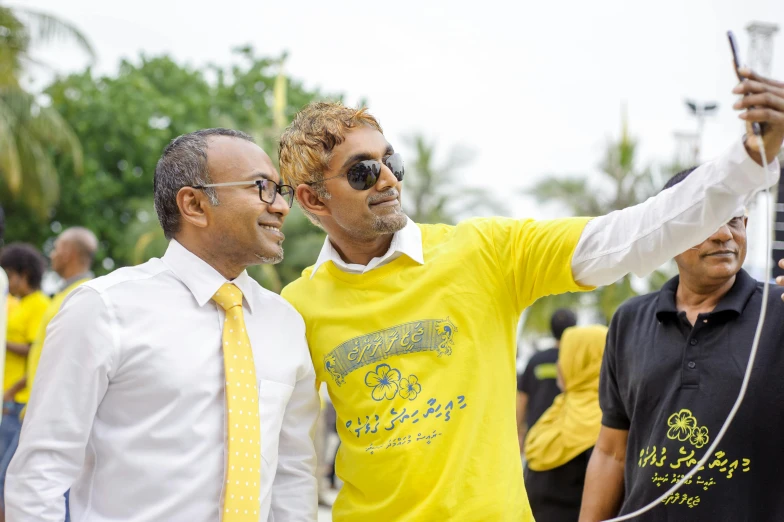 a couple of men standing next to each other, inspired by Ismail Gulgee, pexels contest winner, yellow and black color scheme, sri lanka, taking a selfie, inauguration