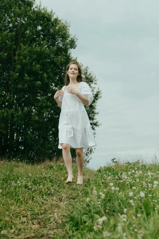 a woman in a white dress walking in a field, an album cover, pexels contest winner, playful pose, low quality footage, portrait of sanna marin, pose 4 of 1 6