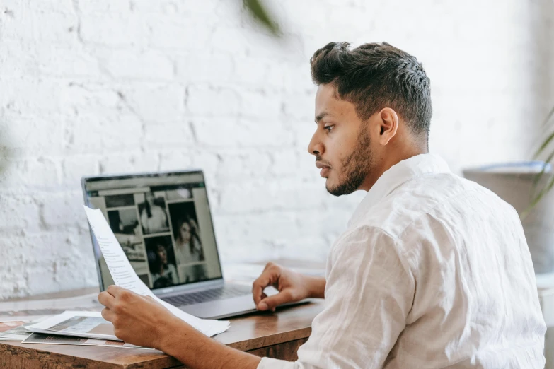 a man sitting at a desk using a laptop computer, a picture, trending on pexels, looking to the right, profile image, 1 2 9 7, pc screen image