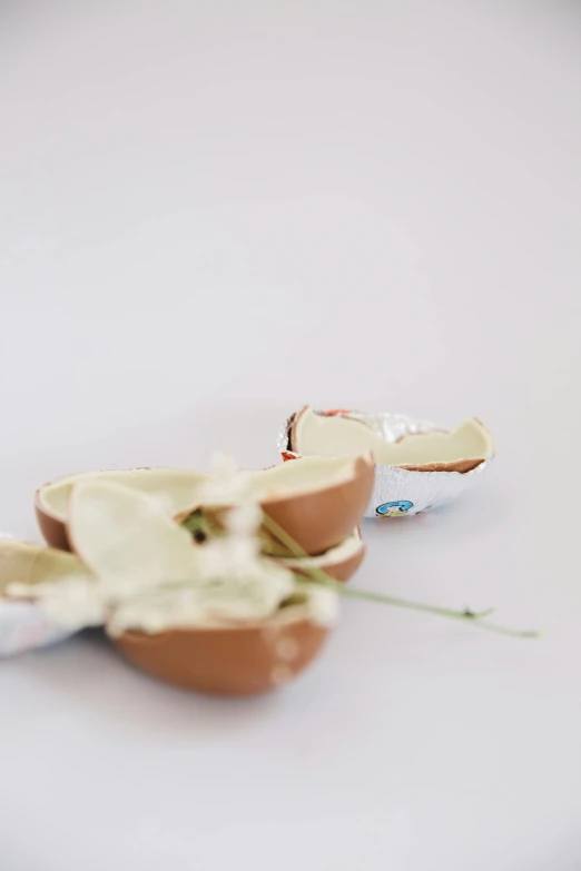 a broken egg sitting on top of a white table, by Ellen Gallagher, unsplash, candy decorations, pulled apart, chocolate, smeared flowers