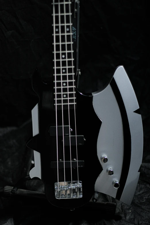 a close up of a bass guitar on a black background, inspired by Ren Bonian, reddit, goth transformers, curved body, metal, oh