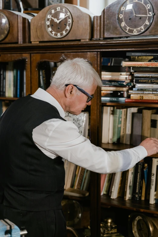 a man that is standing in front of a book shelf, by Peter Churcher, white haired, reading glasses, lpoty, elegantly dressed