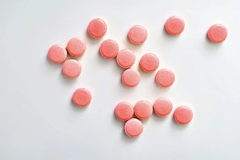 a pile of pink pills sitting on top of a white surface, a picture, by Emma Andijewska, macaron, detailed product image, coral red, top down shot