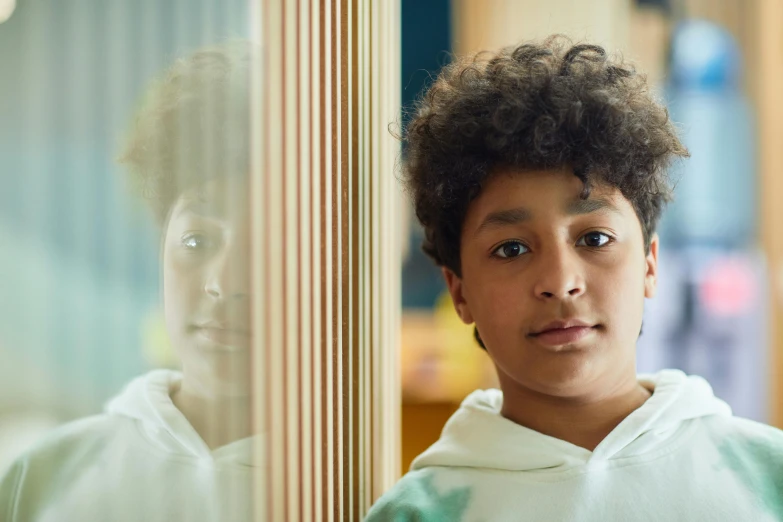 a young boy standing in front of a mirror, an album cover, pexels contest winner, aida muluneh, school class, beautiful natural soft light, mixed race