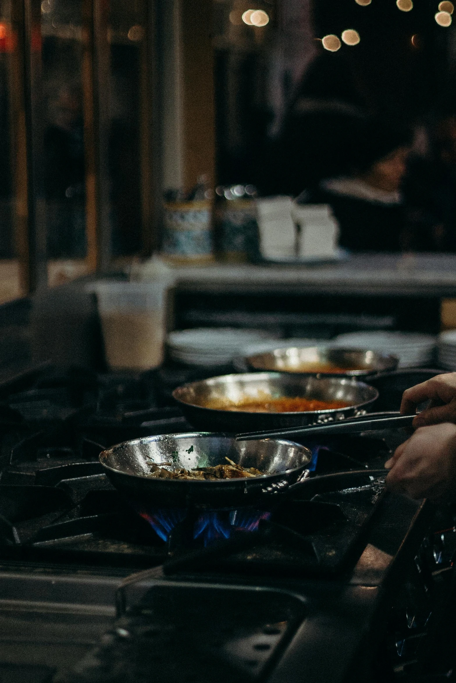a person cooking food on a stove in a kitchen, at a dinner table, restaurant, during the night