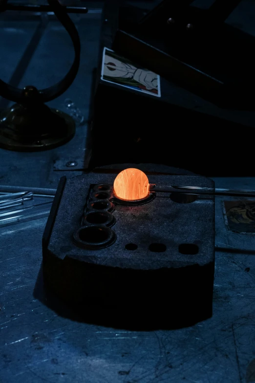 a piece of metal sitting on top of a table, inspired by Joseph Wright of Derby, process art, glowing orbs, sunstone, in a laboratory, production photo