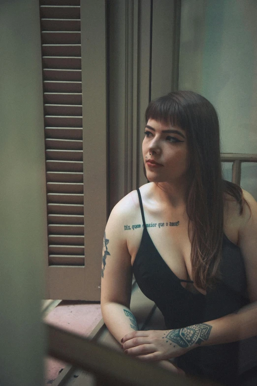 a woman in a black dress sitting on a window sill, an album cover, inspired by Elsa Bleda, pexels contest winner, tattooed body, thicc, lesbians, halfbody headshot