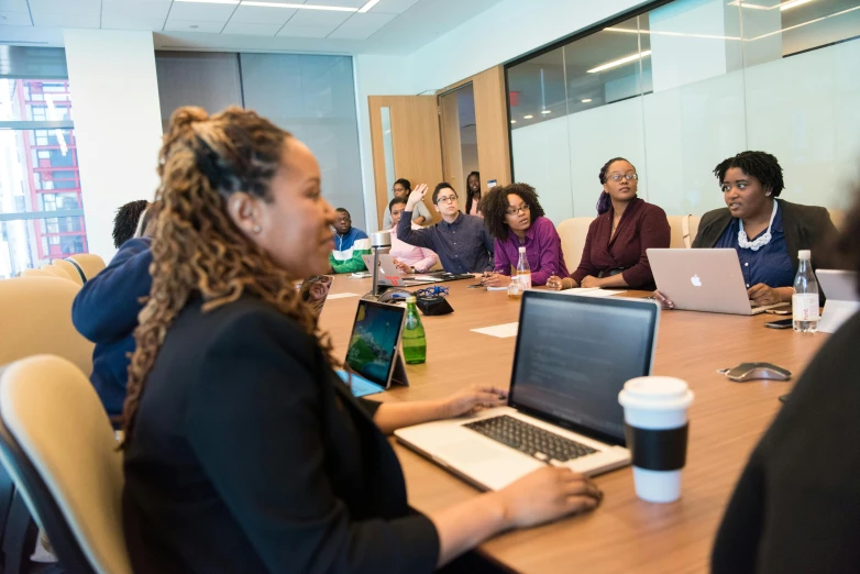 a group of people sitting around a table with laptops, by Carey Morris, unsplash, square, photo of a black woman, in a meeting room, slide show