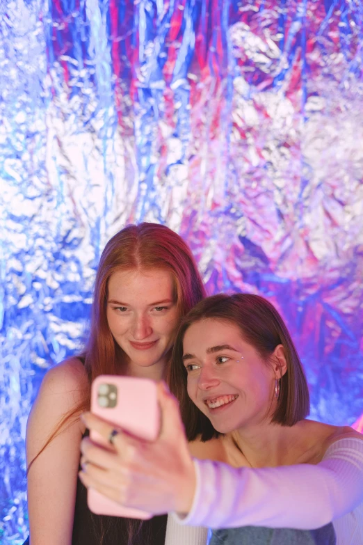 a couple of women standing next to each other taking a picture, trending on pexels, holography, glowing drapes, teenage, freckles on chicks, jelly glow