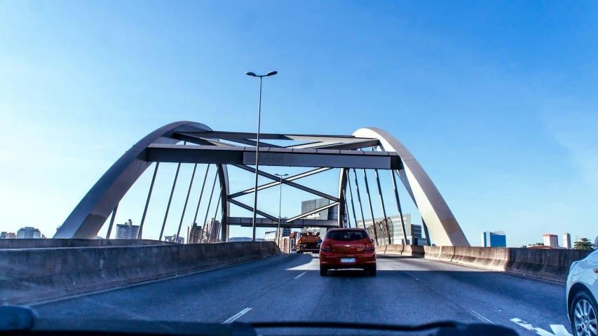 a car driving across a bridge on a sunny day, by Jacob Toorenvliet, pexels contest winner, hurufiyya, steel archways, high traffic, memphis, 1 4 9 3