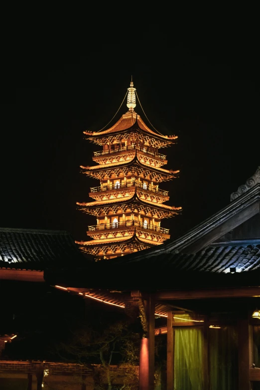 a building lit up at night with a clock tower in the background, inspired by Yang Buzhi, peaked wooden roofs, lead - covered spire, brown, slide show