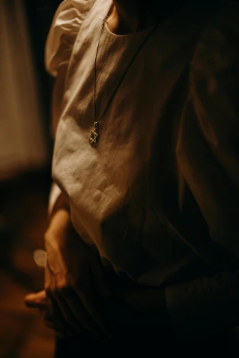 a close up of a person holding a cell phone, inspired by Elsa Bleda, unsplash, renaissance, wearing a white shirt, pendants, captured in low light, indoor picture