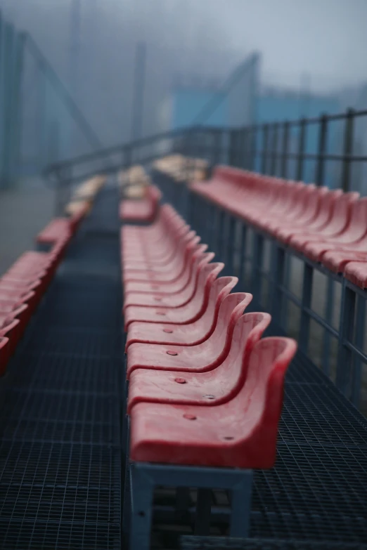 a row of red seats sitting on top of a metal floor, pexels contest winner, plasticien, football, very hazy, square, bridges