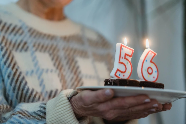 a close up of a person holding a plate with a cake with candles on it, pexels contest winner, figuration libre, 50 years old, alexa65, unreal engine 5 renderered, numerology