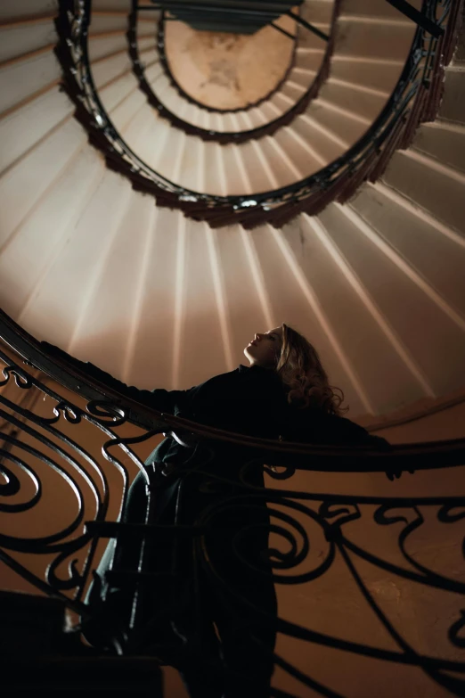 a woman standing at the top of a spiral staircase, inspired by Anna Füssli, pexels contest winner, baroque, low lights, promo image, low angle wide shot, multiple stories