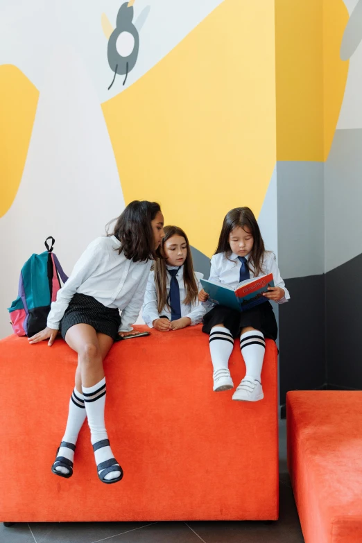 a couple of girls that are sitting on a couch, inspired by Lucas van Leyden, trending on unsplash, ashcan school, colorful uniforms, in school hallway, four stories high, orange grey white