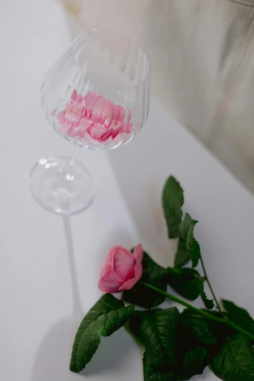 a couple of wine glasses sitting on top of a table, a still life, by Anna Boch, unsplash, romanticism, pink petals fly, low quality photo, bubble bath, high angle close up shot