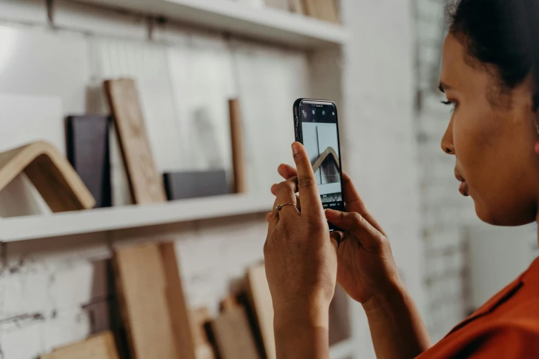 a woman in an orange shirt looking at a cell phone, a picture, trending on pexels, visual art, picture of an interior loft, photo for a store, wood print, photo of a black woman