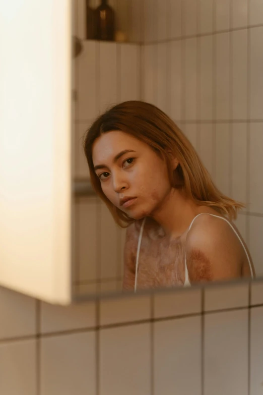 a woman standing in front of a mirror in a bathroom, inspired by Elsa Bleda, antipodeans, burn scar left cheek, silicone skin, furr covering her chest, pokimane