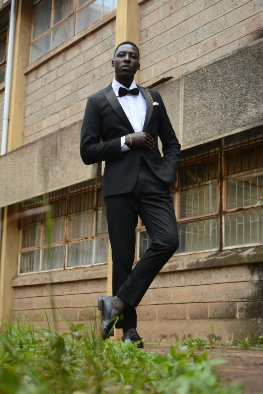 a man in a tuxedo standing in front of a building, unmistakably kenyan, model standing pose, obunga, black main color