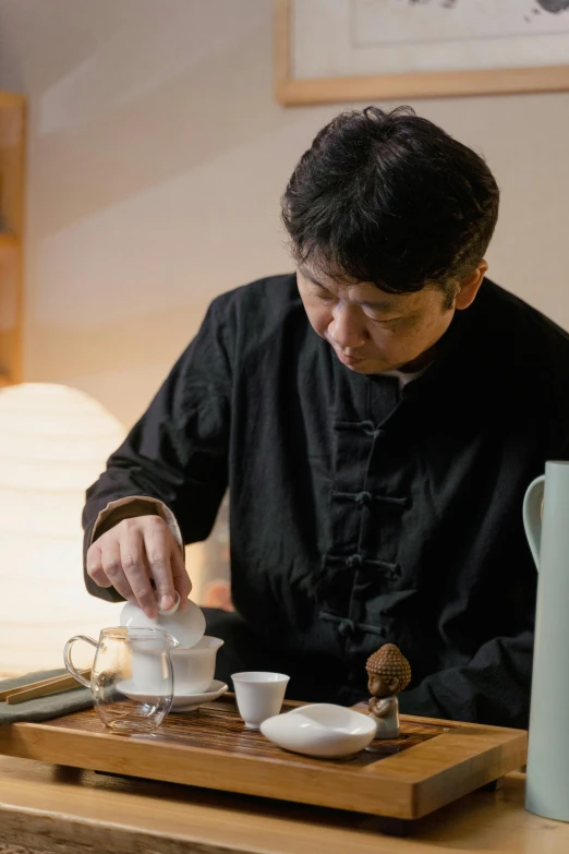 a man sitting at a table preparing a cup of tea, inspired by Li Shixing, square, production photo
