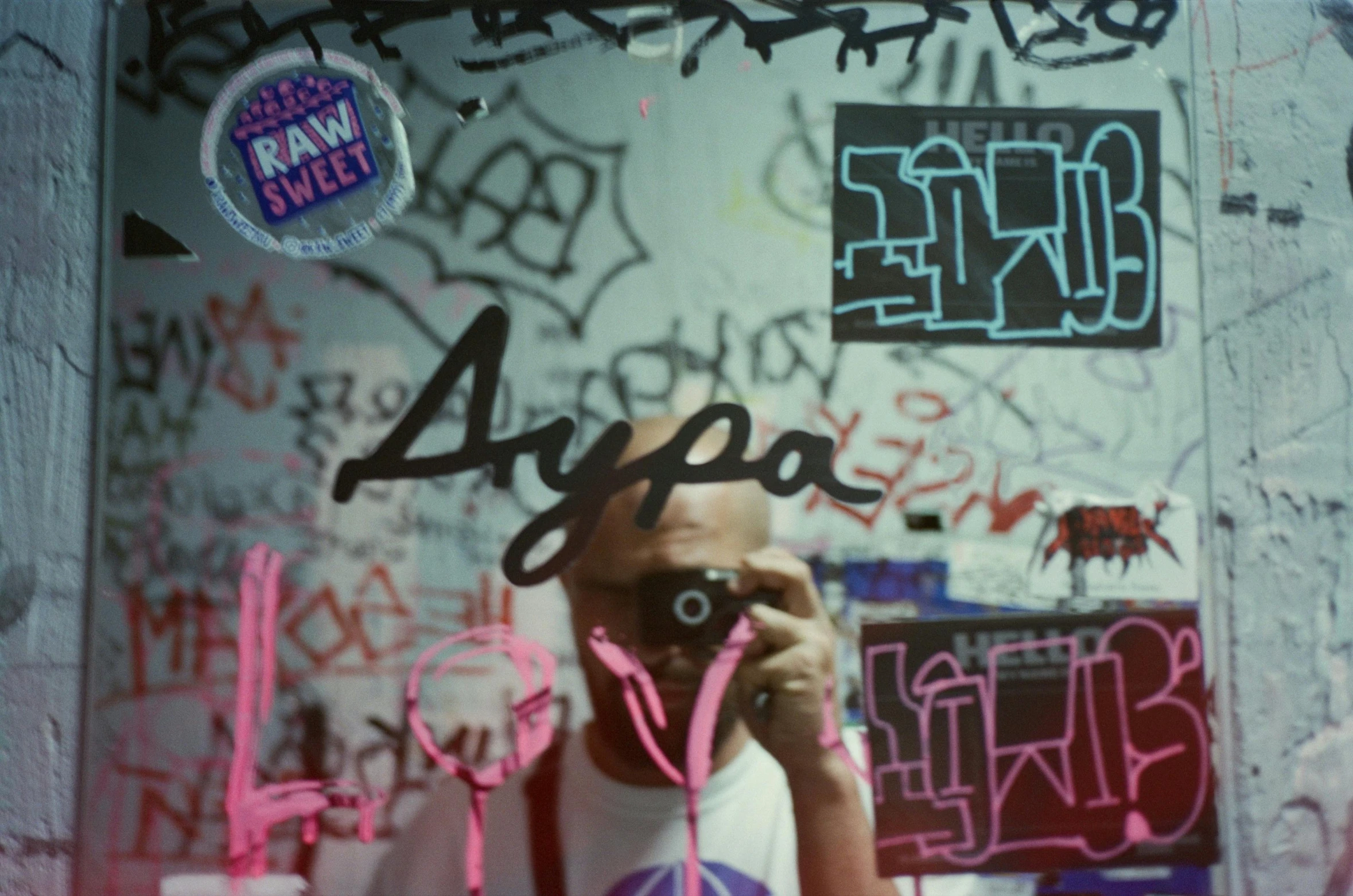 a man taking a picture of himself in a mirror, inspired by Aya Goda, unsplash, graffiti, still from akira (1988), pink, graffiti letters, royo