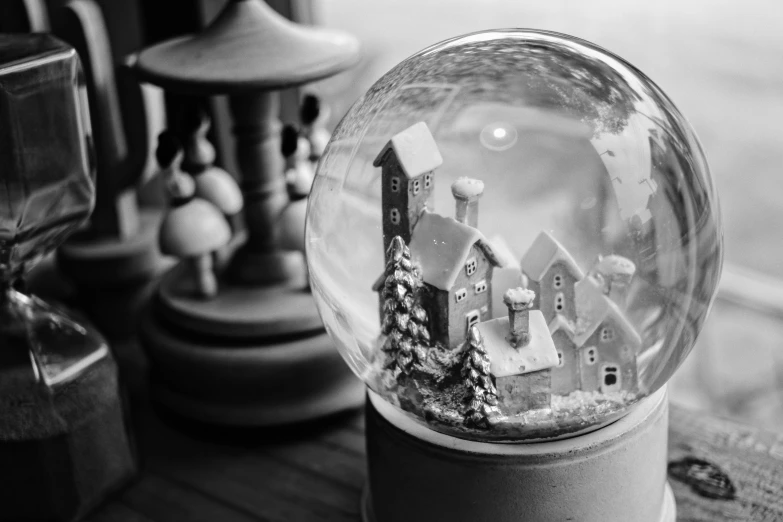 a snow globe sitting on top of a wooden table, a black and white photo, by Adam Marczyński, pexels contest winner, magical realism, miniature porcelain model, nostalgic 8k, spherical, escher