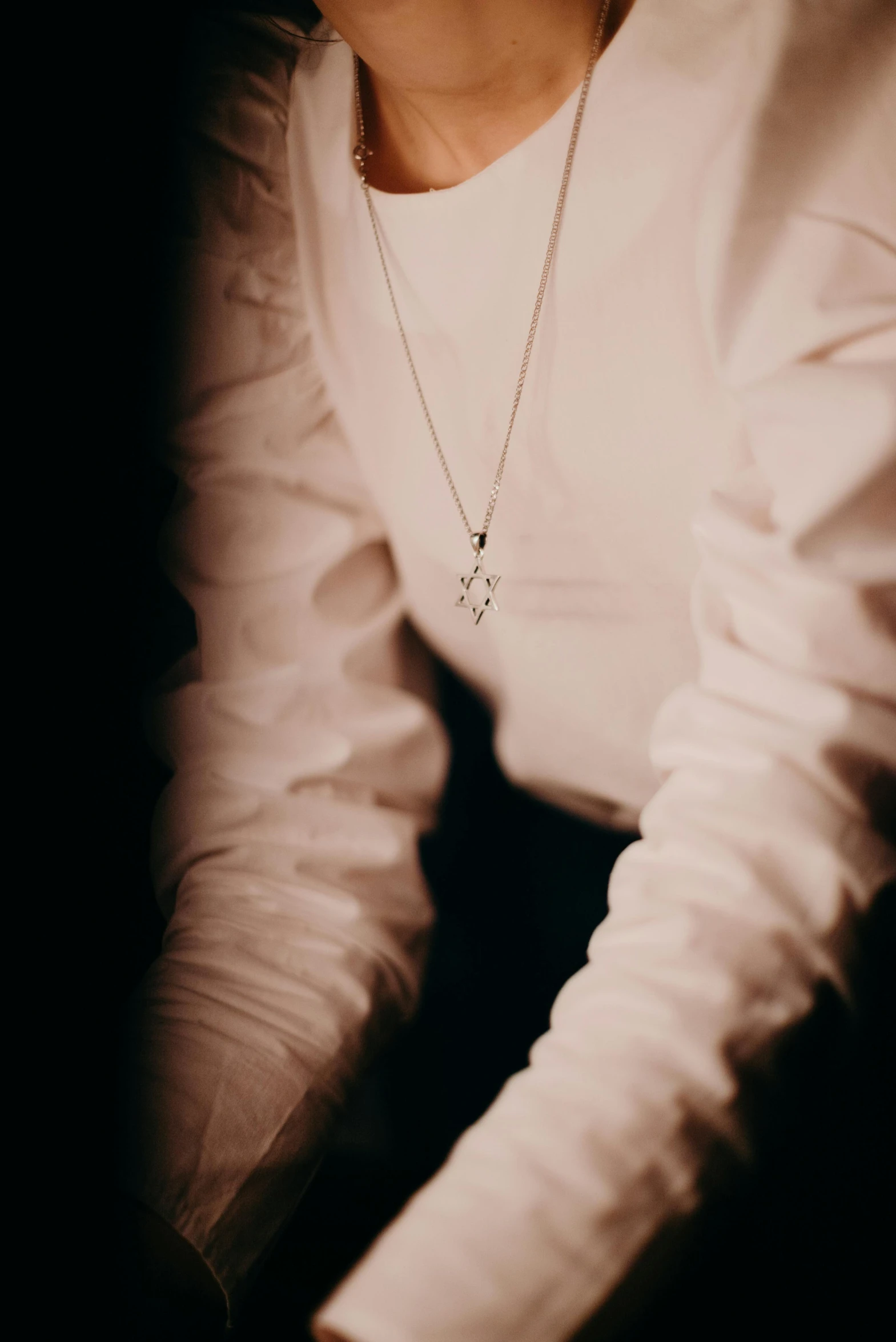 a close up of a person holding a cell phone, a black and white photo, inspired by Elsa Bleda, trending on pexels, renaissance, diamonds around her neck, dressed like a cleric, under a spotlight, pendants