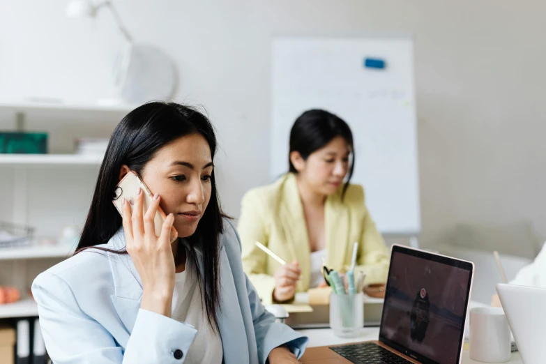 a woman talking on a cell phone while sitting in front of a laptop, a cartoon, trending on pexels, hurufiyya, fiona staples and kinu nishimura, in an call centre office, vietnamese woman, thumbnail