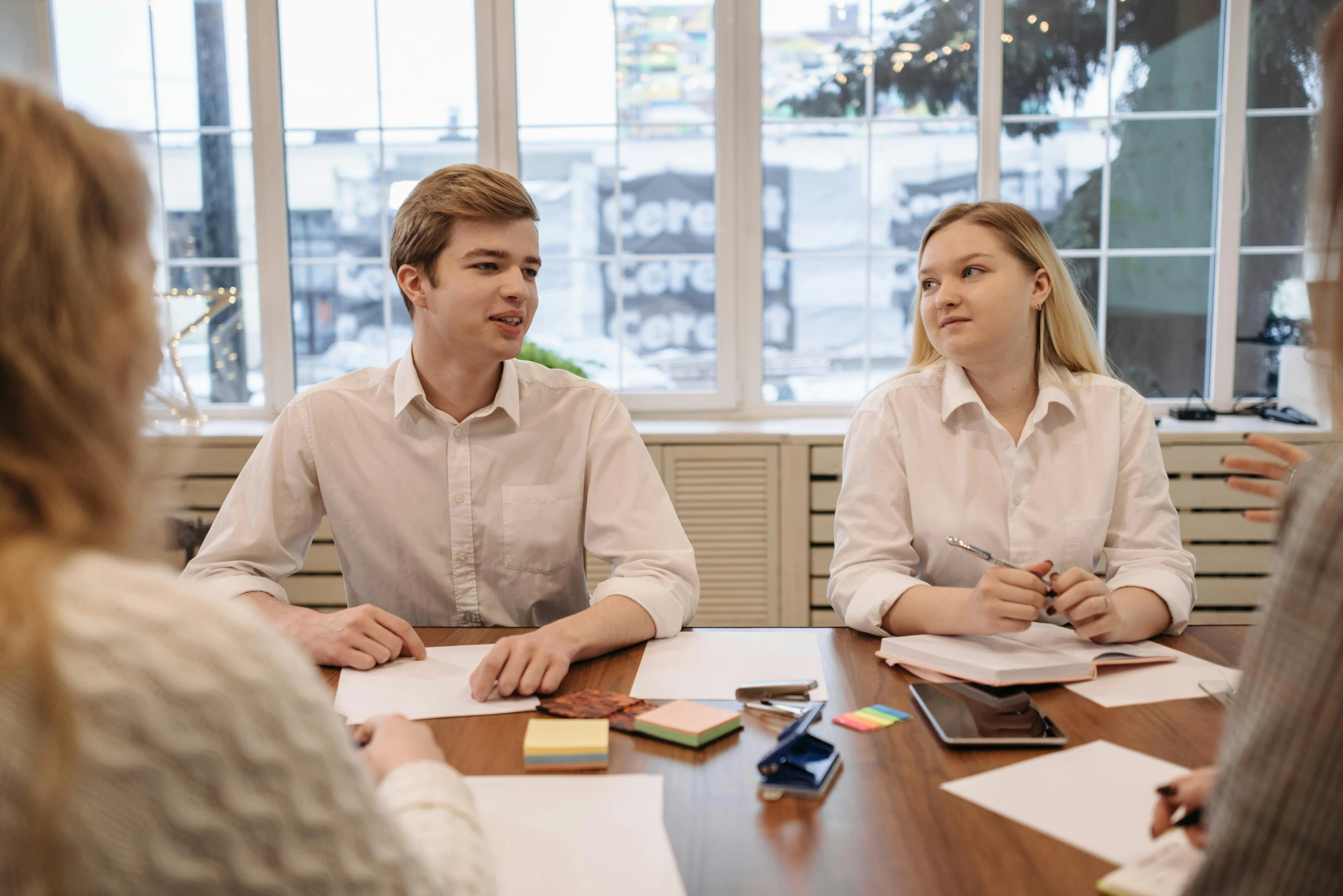 a group of people sitting around a wooden table, on a white table, profile image