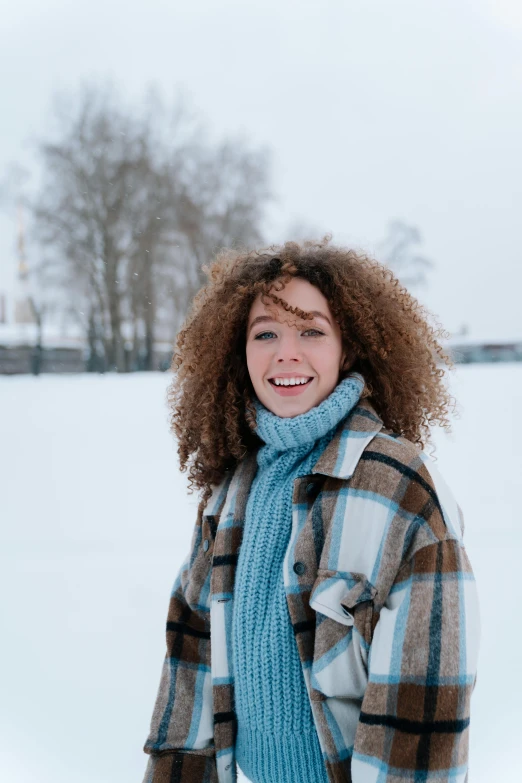 a woman standing in the snow holding a snowboard, pexels contest winner, renaissance, brown curly hair, avatar image, wearing turtleneck, snowy field