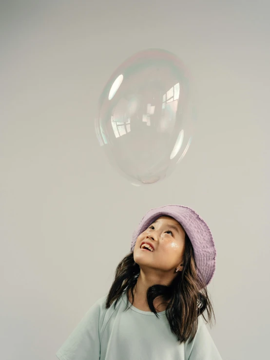 a little girl standing in front of a giant bubble, a picture, by Juliette Leong, trending on pexels, wearing wool hat, ((purple)), janice sung, studio photoshoot