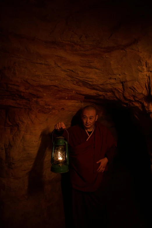 a couple of men standing next to each other in a cave, an album cover, inspired by Steve McCurry, unsplash contest winner, portrait of monk, warm lantern lighting, low colour, maroon